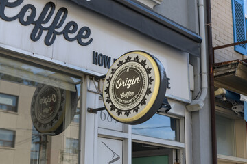 Fototapeta premium wall-mounted round projecting sign outside At Origin Coffee, a coffee shop, located at 687 Mount Pleasant Rd, Toronto