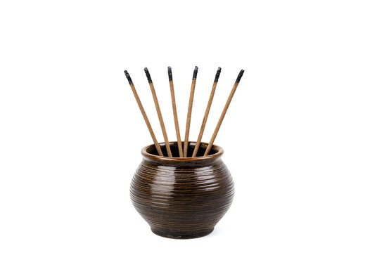 Traditional incense sticks arranged in decorative ceramic holder on white background
