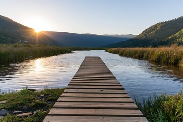 Fototapeta premium Wooden pier on a lake at sunrise with hills and reeds