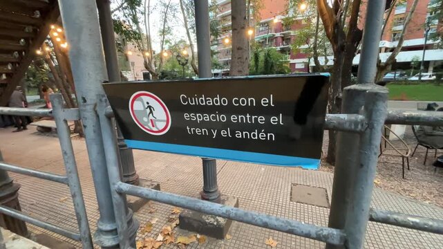 Information sign reading "Mind the gap between train and platform" at Coghlan station, located in Buenos Aires, Argentina.