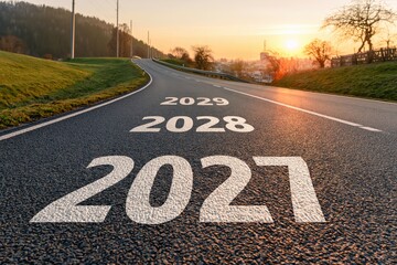 Obraz premium 2027 to 2029 Road with years painted on asphalt leading into a sunset representing future progress and a vision for goal planning
