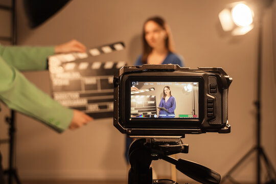 Video production and media creation, professional film crew filming a woman in a studio with a clapperboard for a corporate video or broadcast project