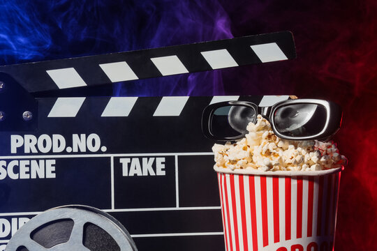 Cinema entertainment and movie industry, film clapperboard with 3d glasses and popcorn bucket in dark studio with blue and red smoke for media production