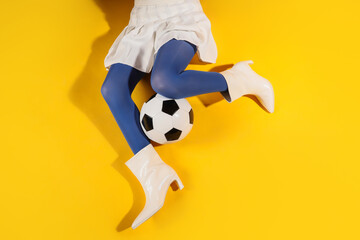 Obraz premium Sports fashion and youth culture, woman in white skirt and blue tights playing with a soccer ball on a bright yellow background for creative advertising