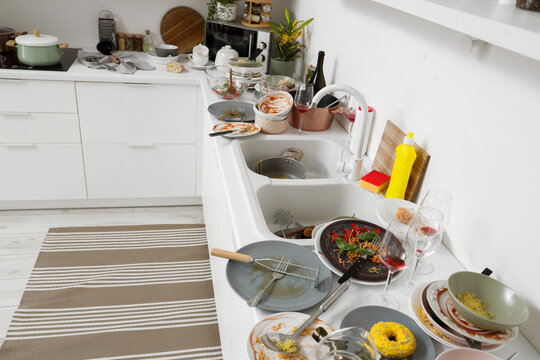 Household chores and domestic stress, messy kitchen sink with dirty dishes and leftover food after a dinner party in a modern home interior