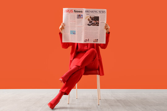 Pandemic news and health crisis, woman in red suit reading newspaper about virus updates and breaking news while sitting on chair against orange background