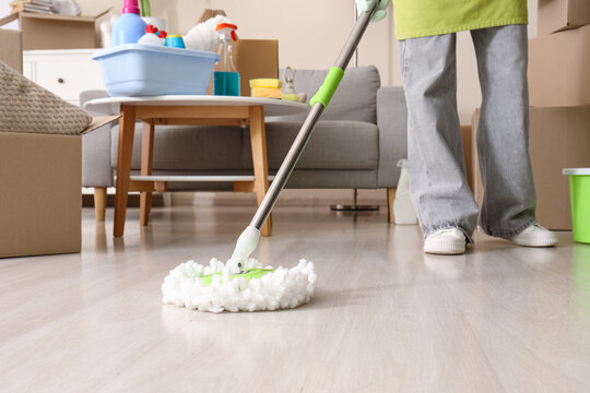 Moving house cleaning, person mopping floor in new home with cardboard boxes and supplies for relocation, spring cleaning and residential maintenance