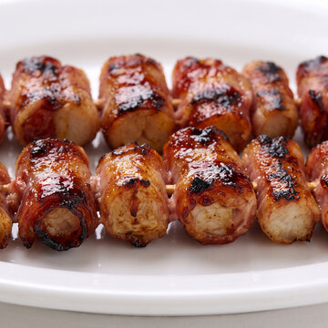 Close up front view of crispy bacon-wrapped meat skewers filling the frame