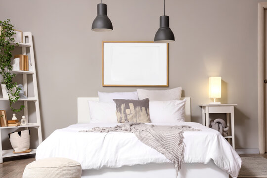 Interior design and home staging, empty picture frame mockup above a cozy bed in a modern bedroom with minimalist decor and warm ambient lighting