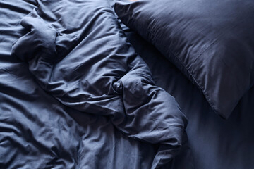 Naklejka na ściany i meble Insomnia and sleep disorder, messy dark blue bed sheets with unmade pillow in morning light