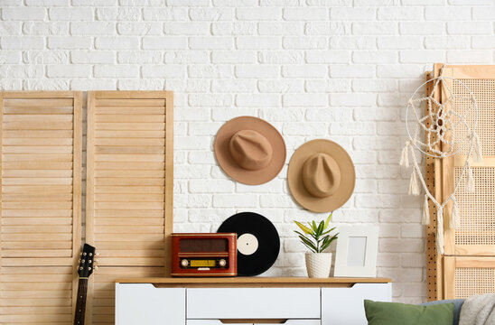 Bohemian interior design and lifestyle, vintage home decor with retro radio and vinyl record on a wooden sideboard against a white brick wall