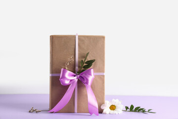 Obraz premium Gift giving and celebration, wrapped present with purple ribbon and dried flowers for birthday or holiday surprise on a clean minimalist background