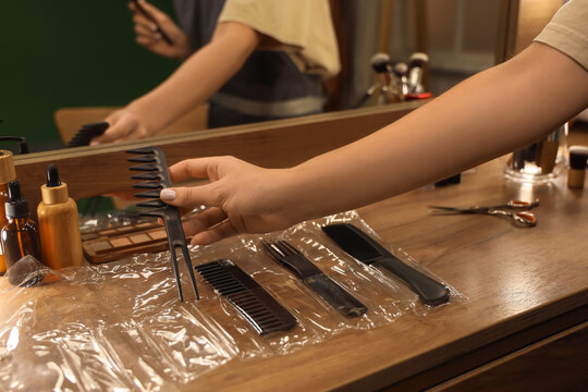 Hair salon services and professional styling, hairdresser choosing a comb from a set of tools on a wooden table in a beauty studio