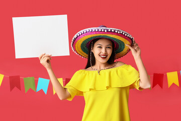 Obraz premium Festa junina celebration and cultural event, happy woman wearing colorful sombrero holding blank sign for copy space on red background with bunting