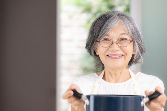 自宅で料理をする元気な日本人の高齢女性、自炊、家事、健康的な食生活、健康寿命、自立したシニアの暮らしカメラ目線の笑顔クローズアップ