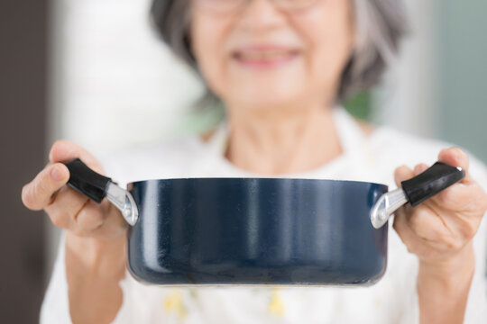 自宅で料理をする元気な日本人の高齢女性、自炊、家事、健康的な食生活、健康寿命、自立したシニアの暮らしカメラ目線の笑顔クローズアップ顔無し