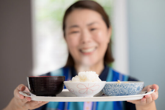食事を配膳する笑顔の介護スタッフ、訪問介護、家事代行で食事を提供のホームヘルパーイメージの顔無し