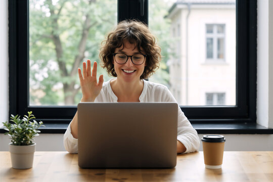 Woman smiling while working remotely on a laptop near a window, representing digital nomad life.