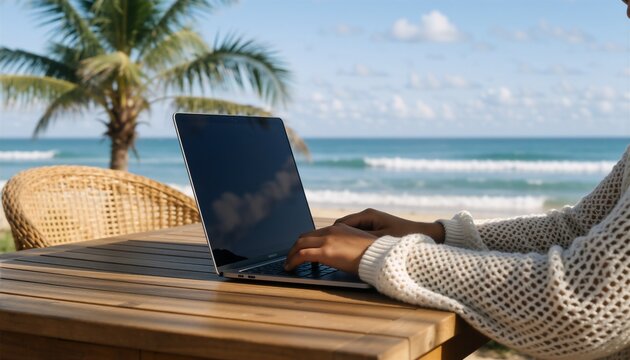 Freelancer working remotely on a laptop at a wooden table overlooking a serene tropical beach scene.