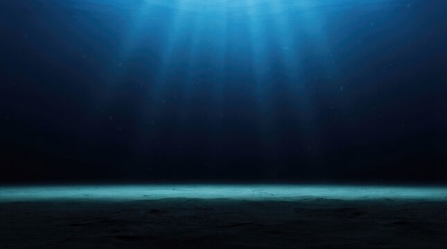 Sunbeams penetrate deep into a dark, vast underwater environment. A horizontal sandy seabed stretches across the bottom of the image, illuminated by the light above.