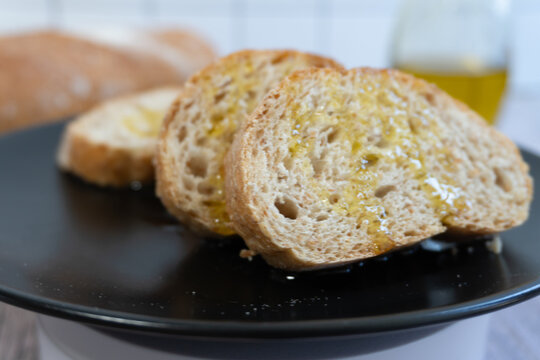 Golden bread slices gleam with olive oil. Crusty texture invites warmth and comfort. Simple meal evokes home and relaxation. Perfect for cozy dinners or healthy eating. Foods look fresh, appealing