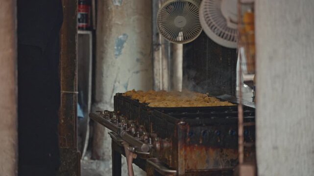 4K Chef turning golden takoyaki octopus balls on traditional iron pan at street food stall.
