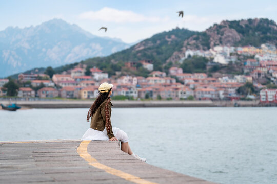 Female tourist relaxing and enjoying the scenic view of the fishing village along the coast at Shazikou in Qingdao
