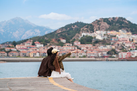 Young couple traveler relaxing and enjoying the scenic view of the fishing village along the coast at Shazikou in Qingdao