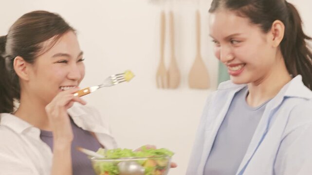 Happy young lesbian couple preparing a healthy fresh vegetable salad together in the modern kitchen.