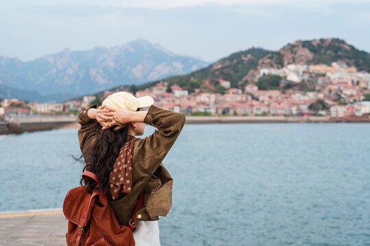 Female tourist relaxing and enjoying the scenic view of the fishing village along the coast at Shazikou in Qingdao