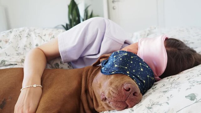 Woman and brown Pit Bull sleeping in bed wearing sleep masks. Daytime sleep. Pet care, comfort, and love. Symbolizes deep bond and caring for animals. Ideal for pet lifestyle content