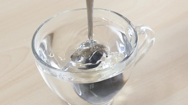 Stirring Water in Glass Cup with Metal Spoon