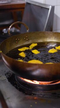 Deep Frying Snacks in Hot Oil Inside Large Metal Wok