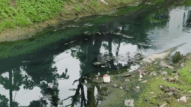 Shallow polluted river with sediment buildup and wastewater discharge, illustrating water contamination, sewage pollution, environmental degradation, ecosystem damage and water management.