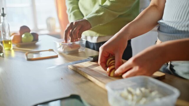 Close up hands packing lunch boxes kitchen. Multiracial couple meal prep home.
