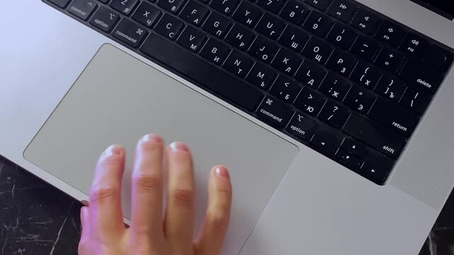 Person using laptop touchpad in close-up, moving fingers across the trackpad at desk for computer navigation, remote work, online tasks, office productivity and everyday digital workflow footage