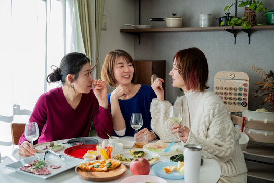 Close-up of smiling women having a fun conversation during a home dinner party with friends.