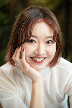 Portrait of a cheerful woman resting her chin on her hand, looking at the camera.