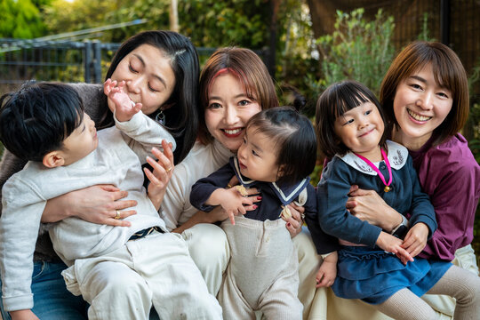 Group photo of mothers and children sharing happy moments outdoors.