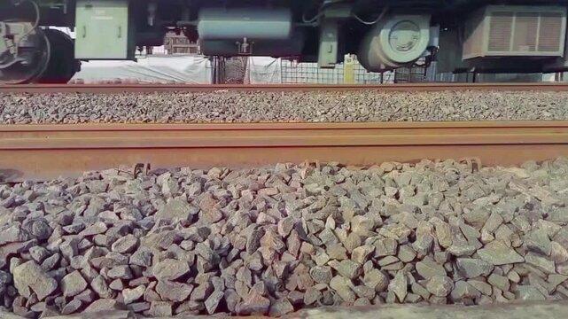 Close-up of train wheels moving on railway track in the morning.