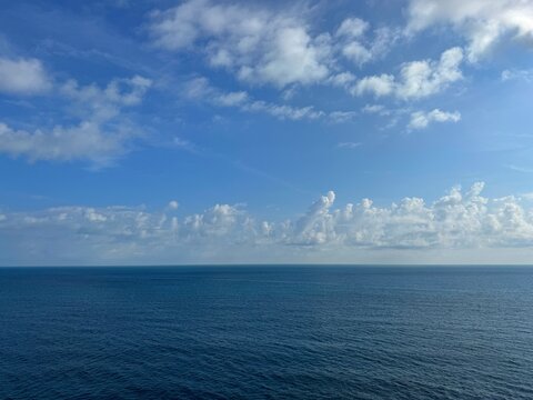 Open sea calm blue water and sky covered with fluffy clouds