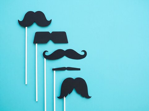 Various black paper mustache and glasses photo booth props on blue background