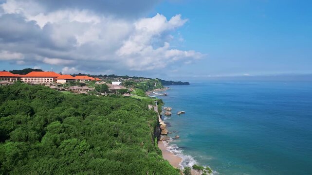 Cliffside ocean retreat. Panoramic ocean view from nearby mountain villas and sandy beaches. Luxury resort perched on cliffs with stunning ocean vistas and colorful rooftops, Jimbaran, Bali
