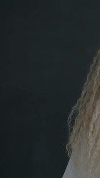 Slow motion portrait of attractive young woman waving hand smiling looking at camera on black studio background. People and communication concept.