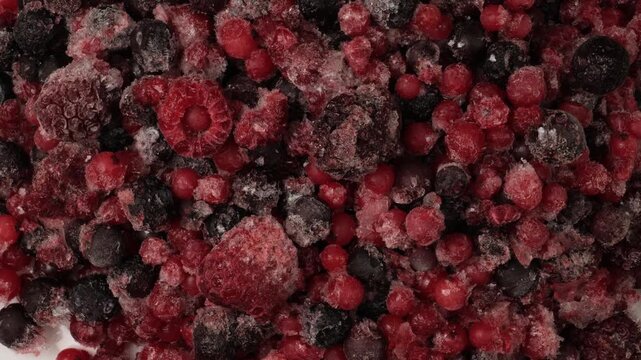 Frozen mixed berries rotating on white background