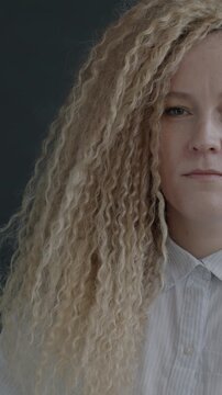 Slow motion portrait of unhappy young woman showing thumbs-down hand gesture looking at camera on black studio background