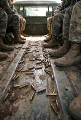 Obraz premium A group of soldiers sit in the back of a dirty military vehicle, surrounded by scattered bullet casings, a stark depiction of conflict and the aftermath of combat.