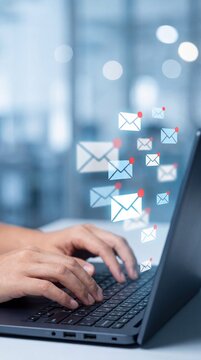 Email messages fly from a laptop as someone types, symbolizing digital communication and connection in a modern, tech-focused environment.