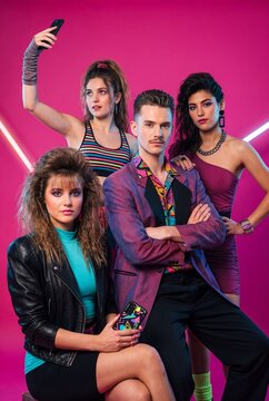 A group of four young adults in vibrant 1980s fashion strike a pose for a selfie, embodying the era's bold style and energetic spirit.