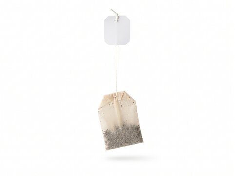 Tea bag hanging with string and paper envelope on white.